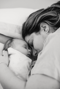 black and white photo of a mother head to head wiht a swaddled baby